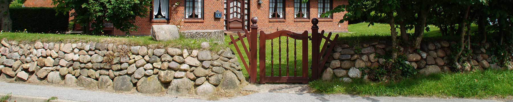 Eingangstor mit Steinmauer zu einem Ferienhaus auf Sylt